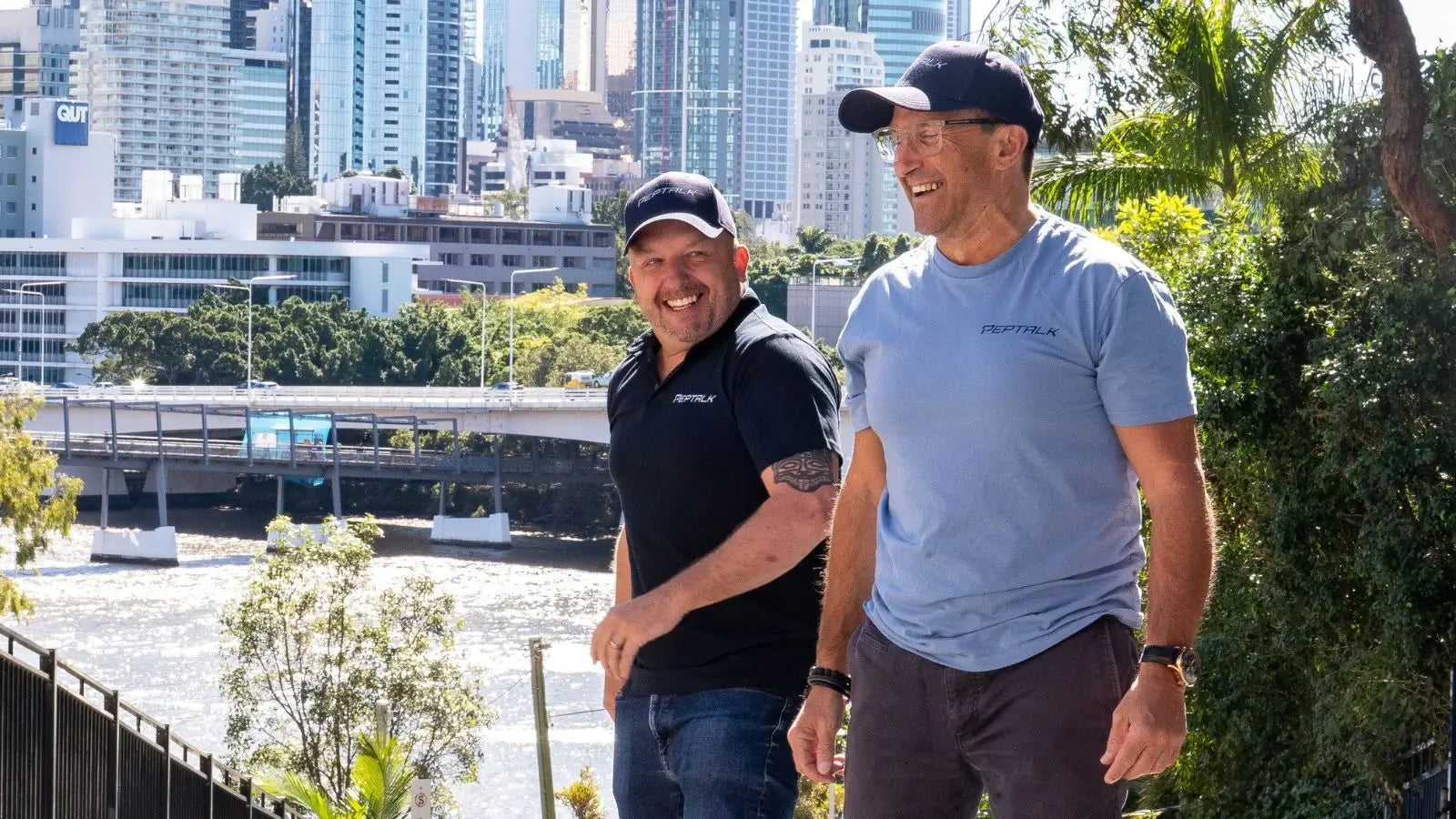 Photo of Matt and Pepe wearing PepTalk shirts while walking outdoors with a cityscape in the background