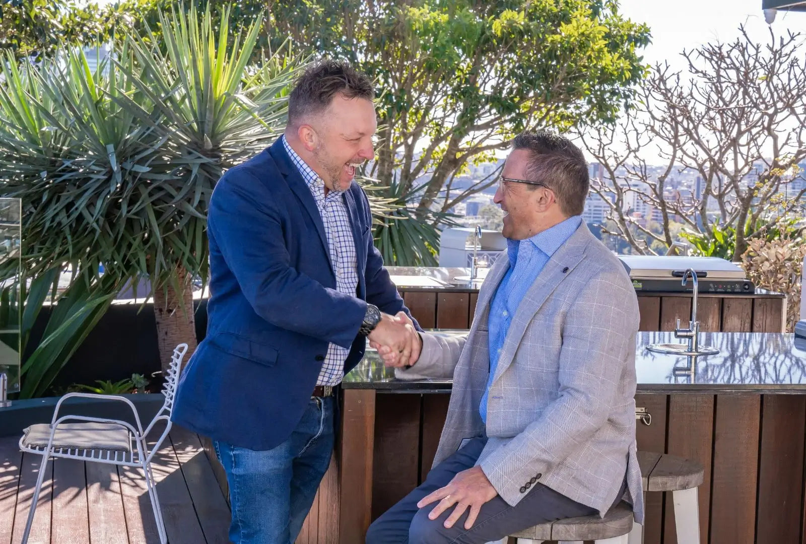 Photo of Pepe and Matt shaking hands with greenery and cityscape in the background